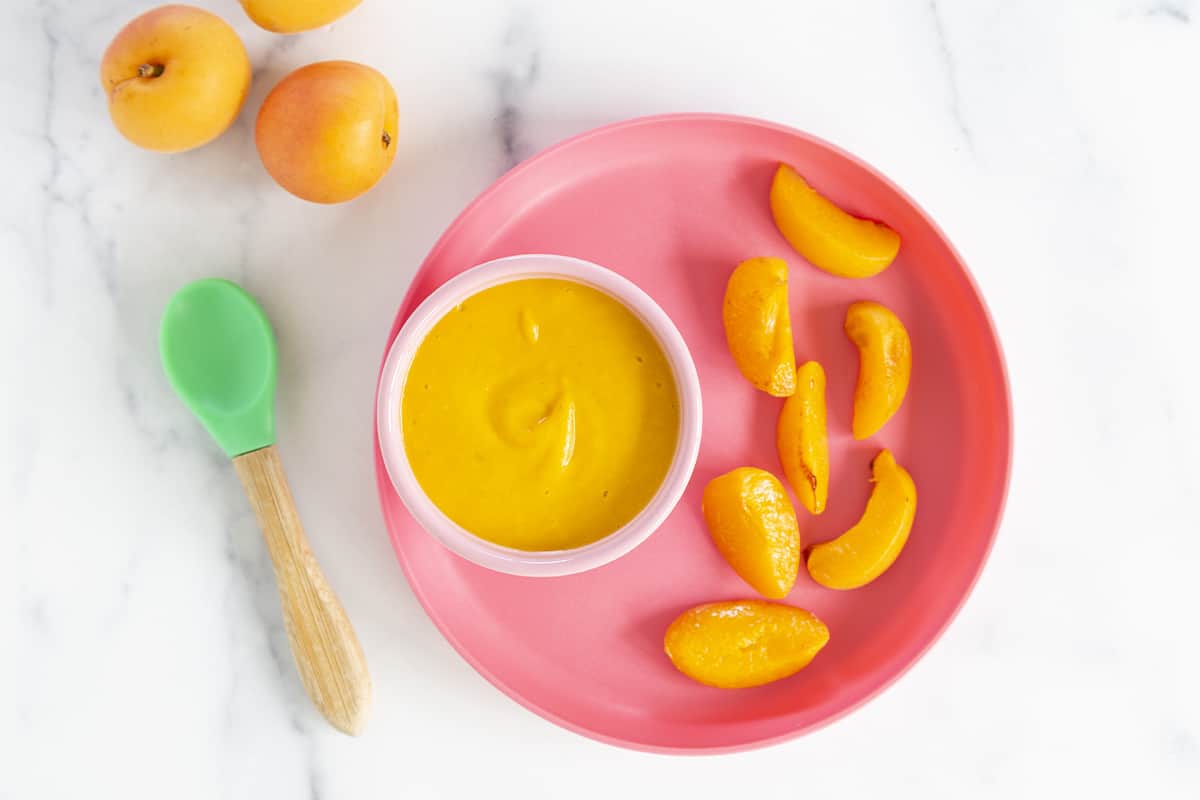 Apricot in puree and in cooked slices on red plate for apricot baby food