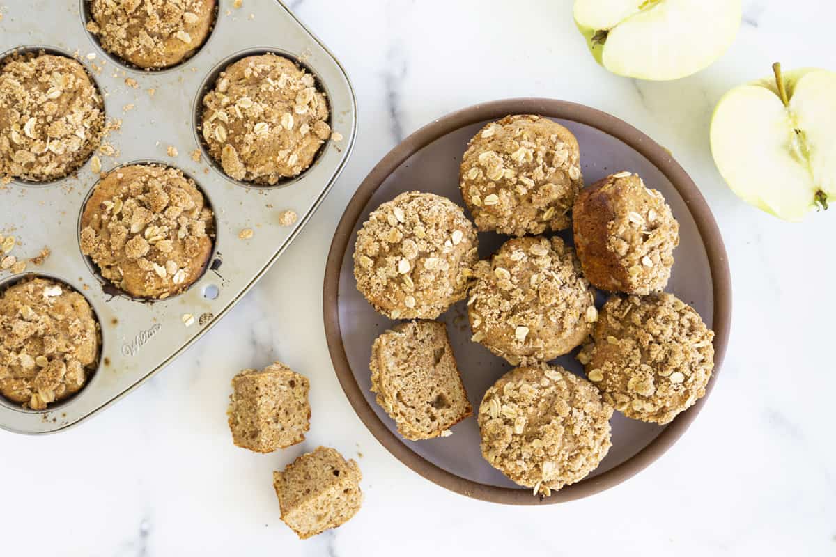 apple cinnamon muffins in pan and stacked on grey plate