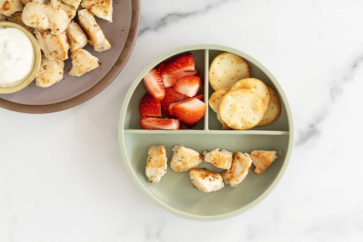 Chicken bites on kids plate with sides.