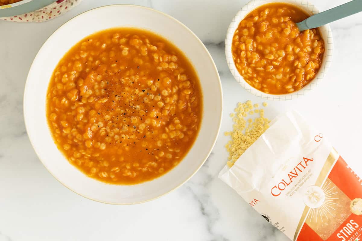 Pastina soup in two bowls with pasta on side.